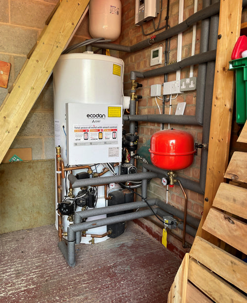 Ecotherm hot water cylinder with copper pipes gray insulation and a red expansion vessel in a utility room.